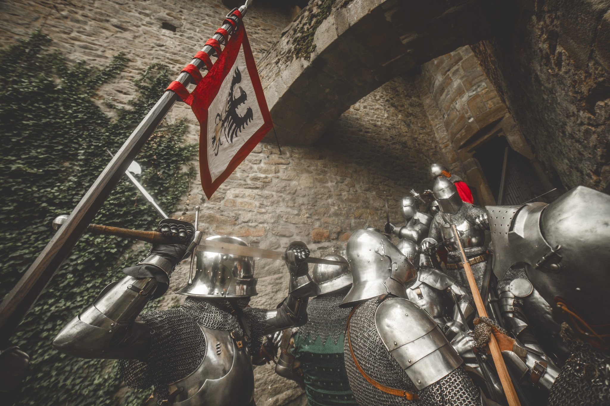 Adeptus fighters under a castle archway with a heraldic banner